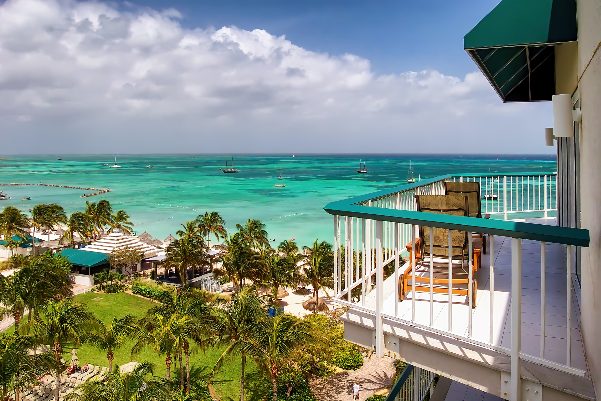 Beautiful balcony view overlooking the blue-green ocean & palm trees in Aruba